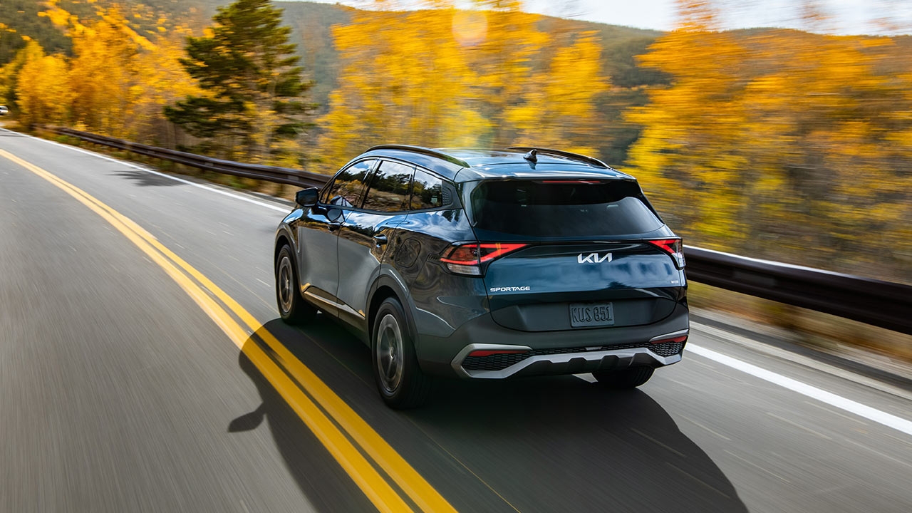 Vue 3/4 arrière sur le Kia Sportage 2024 sur la route en automne.